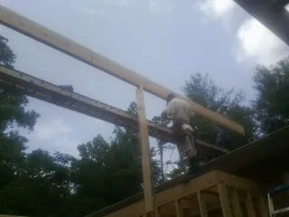 Carpenter setting a ridge beam over a new addition frame — Ice Dam Removal by Roofing Brothers in Blencoe