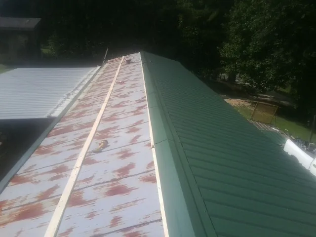 Old rusted panels beside newly installed green metal roofing — Wind Damage Roof Repair by Roofing Brothers in Blencoe