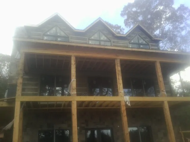 Dormers and porch framing on a large log home under construction — Roof Coating work by our crew in Blencoe