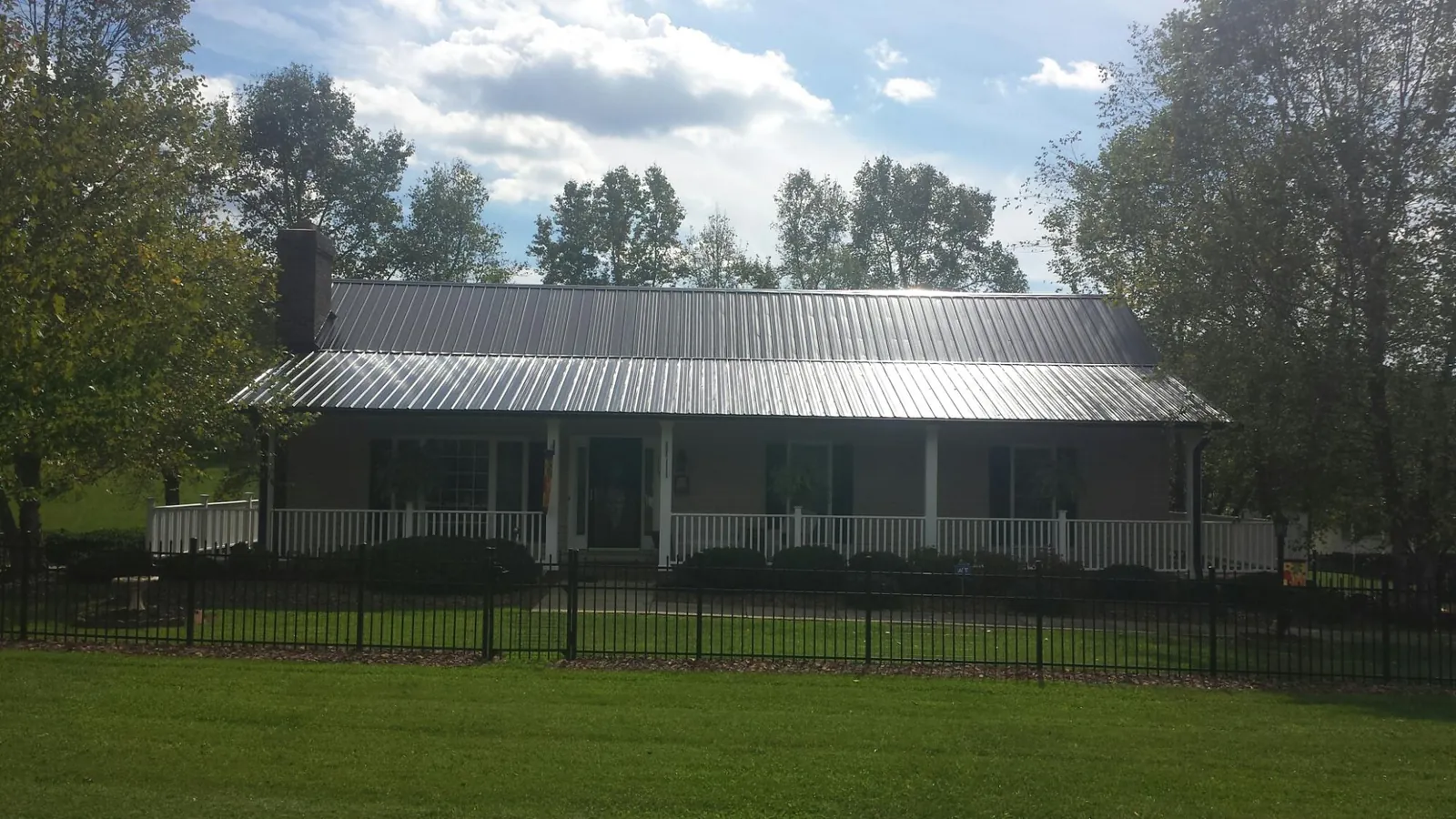 Gray metal roof on a brick ranch with a full width front porch — Gutter Guard Installation work by our crew in Blencoe